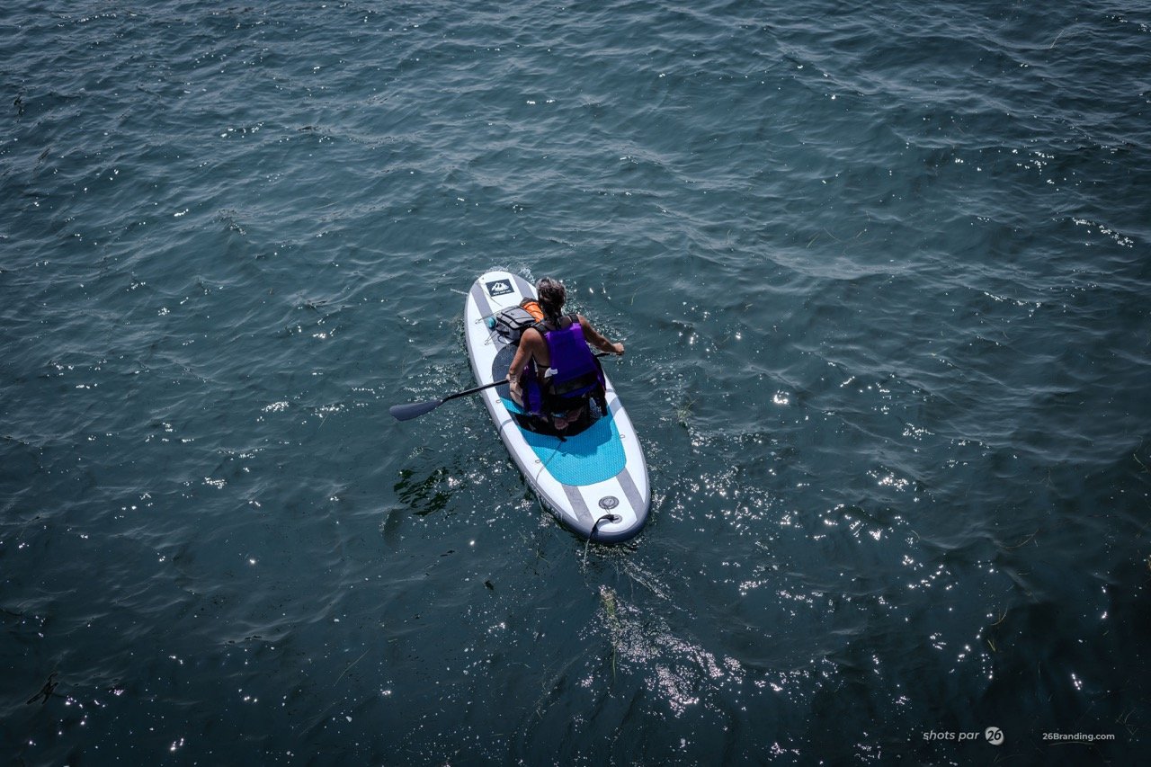 Aerial photography of a person paddleboarding on blue water.
